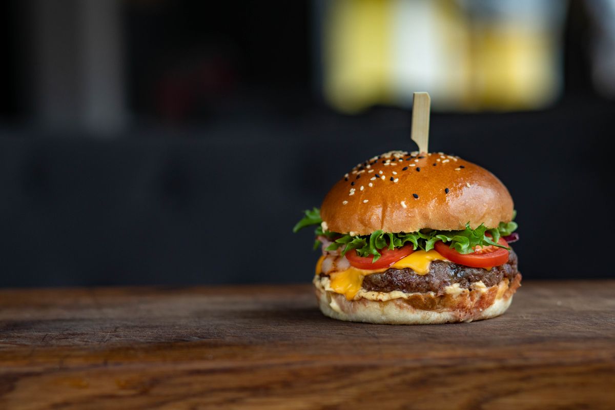 A cheeseburger on a wooden board, the kind served at the Blue Moon Burger Bash